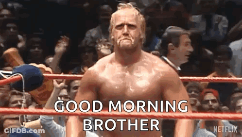 A Shirtless Wrestler Is Standing In A Wrestling Ring With A Crowd Behind Him And Says `` Good Morning Brother '' . GIF