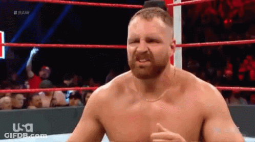 A Shirtless Wrestler Is Standing In A Wrestling Ring With A USA Logo Behind Him GIF