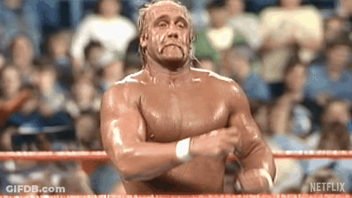 A Shirtless Wrestler Is Standing In A Wrestling Ring With His Hands Crossed . GIF