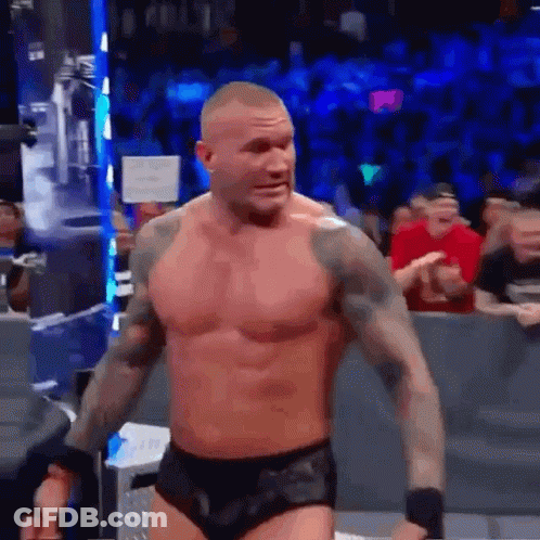 A Shirtless Wrestler Is Standing In Front Of A Crowd In A Ring . GIF