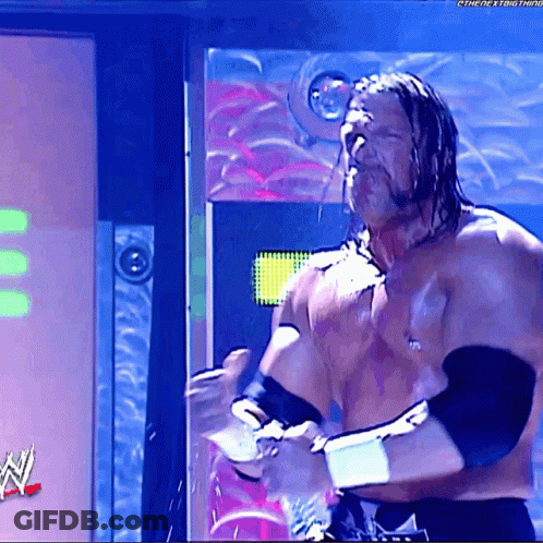 A Shirtless Wrestler Is Standing In Front Of A Sign That Says ' The Next Thing ' On It GIF