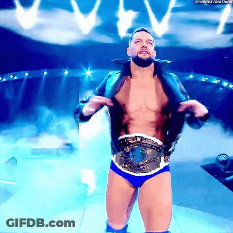 A Shirtless Wrestler Is Standing On A Stage With A Belt Around His Waist .. GIF