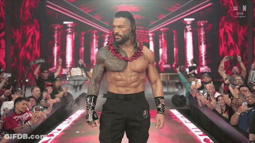 A Shirtless Wrestler Is Walking Down A Ramp With A Crowd Behind Him And A Sign That Says W In The Background GIF