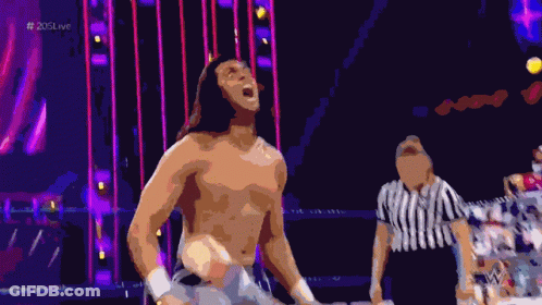 A Shirtless Wrestler Stands In A Ring With A Referee And The Hashtag # 205Live On The Bottom GIF