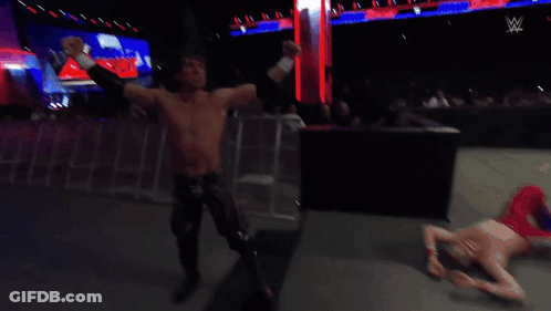 A Shirtless Wrestler Stands In A Wrestling Ring Watching Another Wrestler GIF
