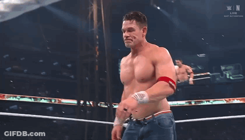 A Shirtless Wrestler Stands In A Wrestling Ring With A Banner That Says Smackdown On It GIF