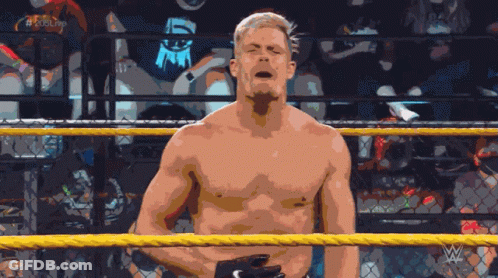A Shirtless Wrestler Stands In A Wrestling Ring With The Letters W On The Bottom Right Corner GIF