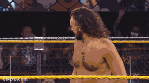 A Shirtless Wrestler Stands In A Wrestling Ring With The Letters W On The Bottom Right GIF