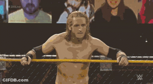 A Shirtless Wrestler Stands In A Wrestling Ring With The Letters W On The Bottom Right GIF