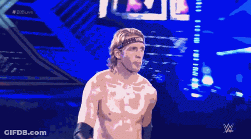 A Shirtless Wrestler Stands In Front Of A Crowd With The Hashtag # 205Live On The Bottom GIF