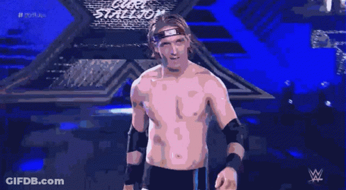 A Shirtless Wrestler With A Bandana On His Head Stands In Front Of A Blue Background GIF