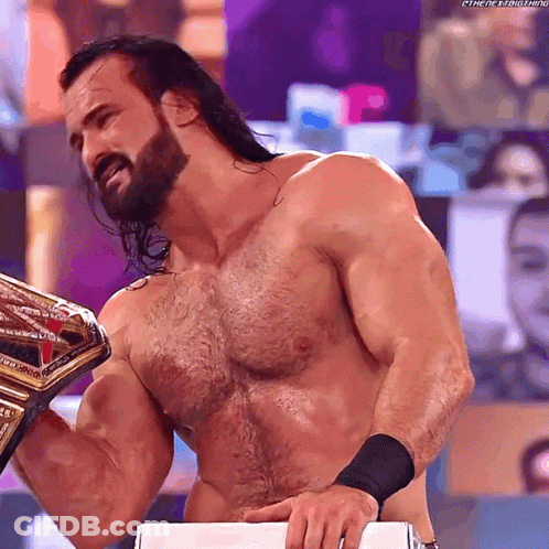 A Shirtless Wrestler With A Beard Is Holding A Wrestling Championship Belt GIF