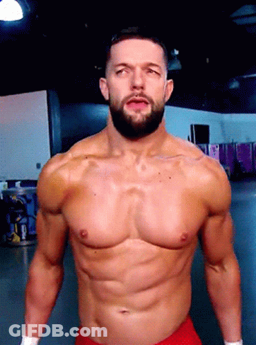 A Shirtless Wrestler With A Beard Is Standing In A Gym GIF