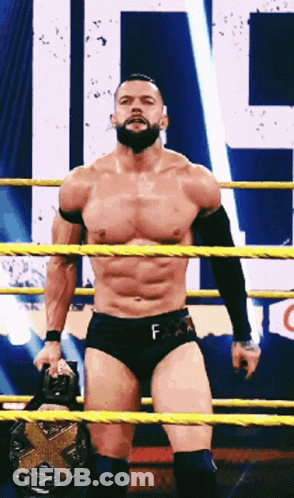 A Shirtless Wrestler With A Beard Is Standing In A Ring Holding A Belt . GIF