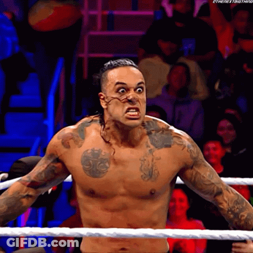 A Shirtless Wrestler With A Tattoo On His Chest Is Standing In The Ring GIF