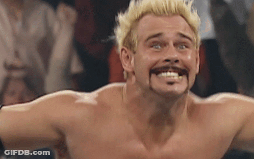 A Shirtless Wrestler With Blonde Hair And A Mustache Making A Funny Face GIF