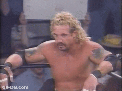 A Shirtless Wrestler With Blonde Hair And Tattoos Is Standing In A Ring . GIF