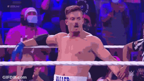 A Shirtless Wrestler With The Word Killer On His Shorts Stands In A Wrestling Ring GIF