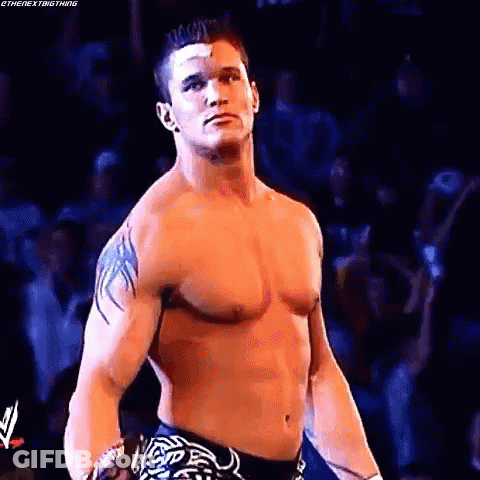 A Shirtless Wrestling Wrestler With A Bandage On His Forehead Is Standing In Front Of A Crowd . GIF
