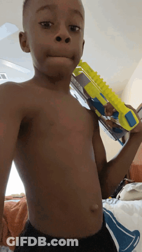 A Shirtless Young Boy Is Holding A Toy Gun GIF