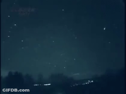 A Shooting Star Is Flying Through A Dark Night Sky . GIF