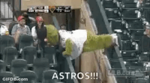 A Shrek Mascot Is Sitting In The Stands At A Baseball Game With A Group Of People . GIF