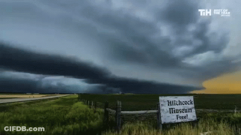 A Sign That Says Hitchcock Museum Free In Front Of A Storm GIF