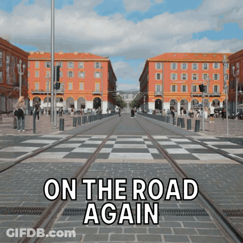 A Sign That Says On The Road Again In Front Of A Busy Street GIF