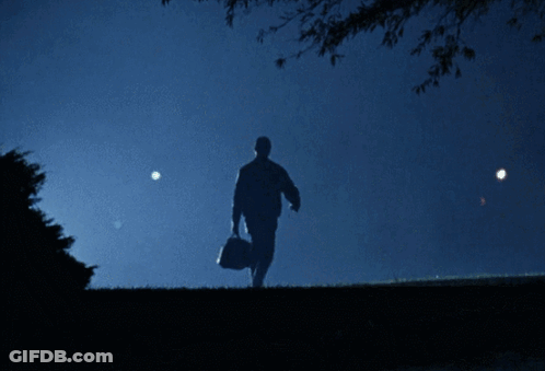A Silhouette Of A Man Carrying A Bag In A Dark Field GIF