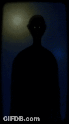 A Silhouette Of A Man In A Hat Walking In The Dark GIF