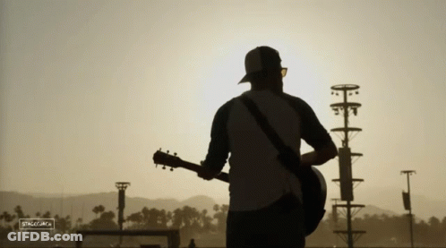A Silhouette Of A Man Playing A Guitar With A Sign That Says ' Silhouette ' On It GIF