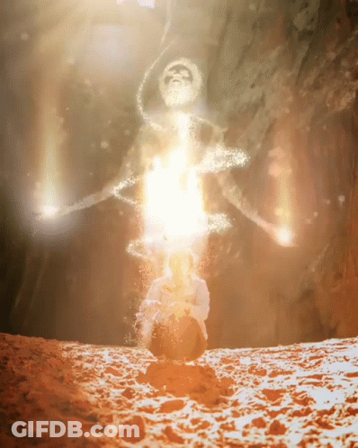 A Silhouette Of A Man Sitting In The Sand With A Light Coming Out Of His Head GIF