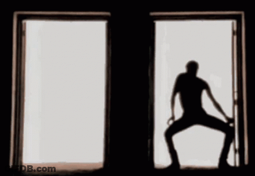 A Silhouette Of A Man Standing In An Open Door GIF