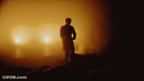 A Silhouette Of A Man Standing In Front Of A Glowing Light GIF