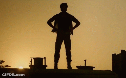 A Silhouette Of A Man Standing With His Hands On His Hips At Sunset GIF