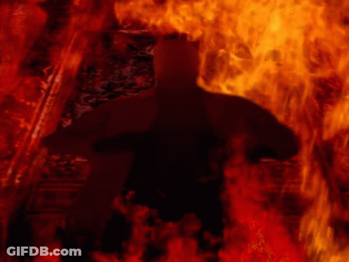 A Silhouette Of A Person In A Dark Room With Fire Behind Them GIF