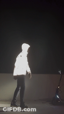 A Silhouette Of A Person In A Reflective Jacket Is Visible In The Dark GIF