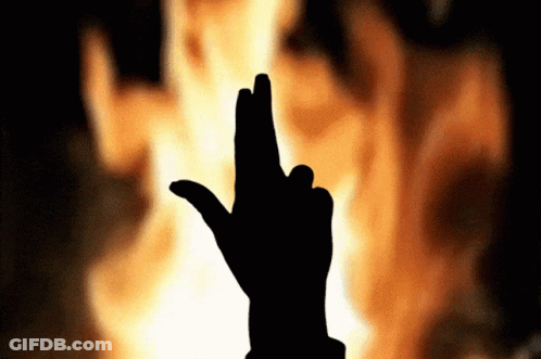 A Silhouette Of A Person 'S Hand With Their Fingers Crossed In Front Of A Fire GIF