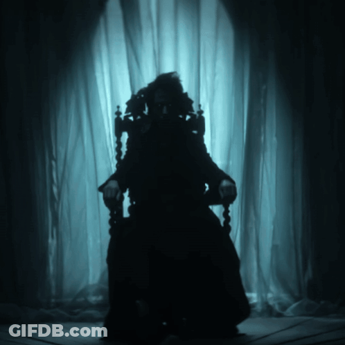 A Silhouette Of A Person Sitting In A Dark Room GIF