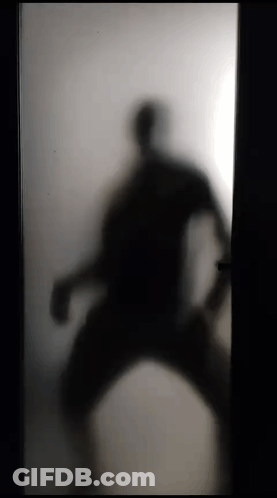 A Silhouette Of A Person Standing In A Doorway Behind A Frosted Glass Door . GIF