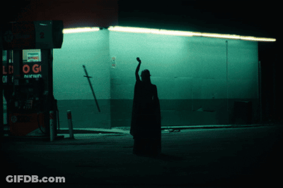 A Silhouette Of A Person Standing In Front Of A Gas Station With A Sign That Says Pepsi GIF