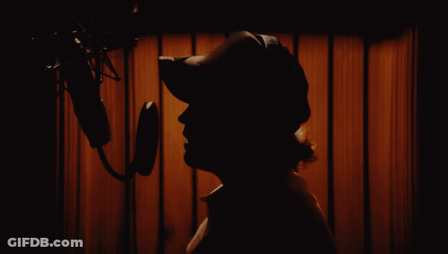 A Silhouette Of A Person Standing In Front Of A Microphone GIF