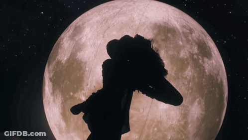 A Silhouette Of A Person Standing In Front Of The Full Moon GIF
