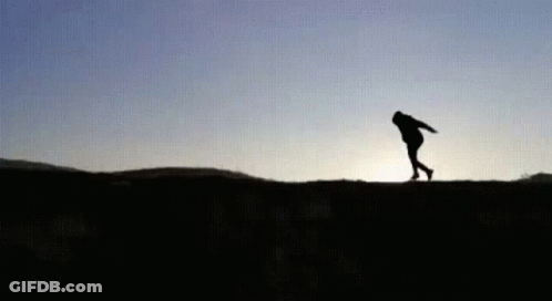 A Silhouette Of A Person Standing On Top Of A Hill . GIF