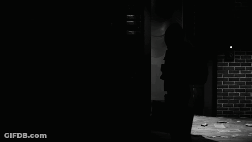 A Silhouette Of A Person Wearing A Hooded Jacket In The Dark GIF