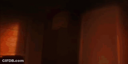 A Silhouette Of A Woman With Glowing Eyes Is Standing In An Open Doorway GIF