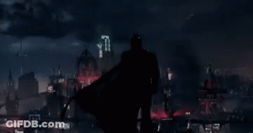 A Silhouette Of Batman Is Standing In Front Of A City GIF