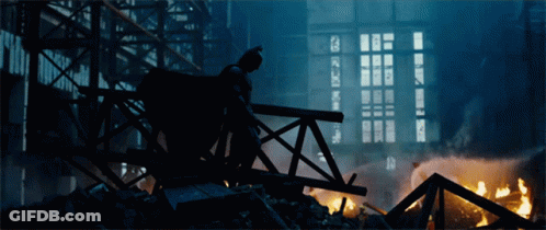 A Silhouette Of Batman Standing On A Bridge In Front Of A Building GIF