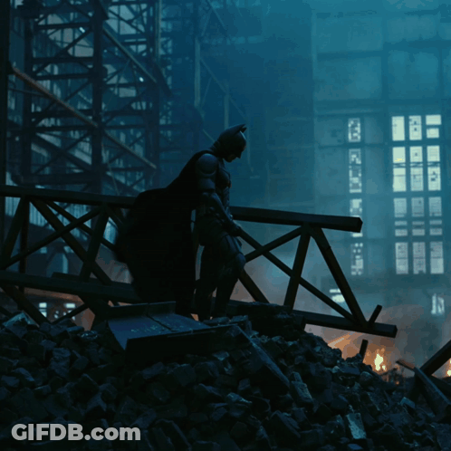 A Silhouette Of Batman Standing On A Bridge With A Building In The Background GIF