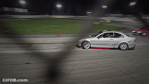A Silver Car Is Driving On A Dirt Road At Night GIF